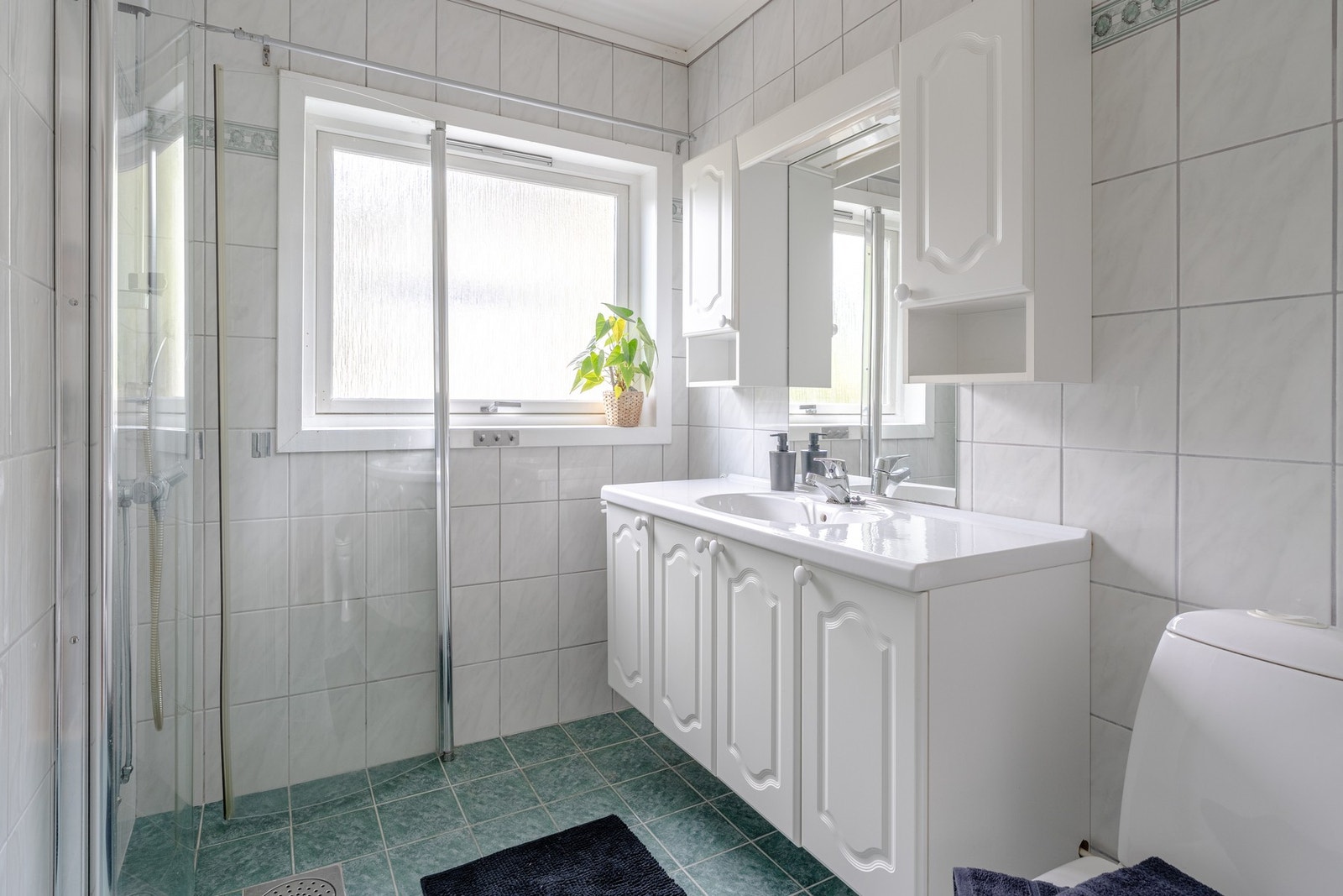 Badet er innredet med toalett, baderomsinnredning med servant og dusj med glassvegger. Galleribilde