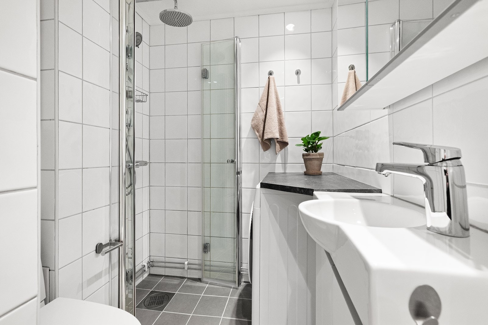 Tidløst bad med nye varmekabler fra 2025 og gulvvarme. Badet er utstyrt med mekanisk avtrekk, opplegg for vaskemaskin, innfellbare dusjdører, wc og servantskap med ettgreps blandebatteri fra FM Mattsson. Galleribilde