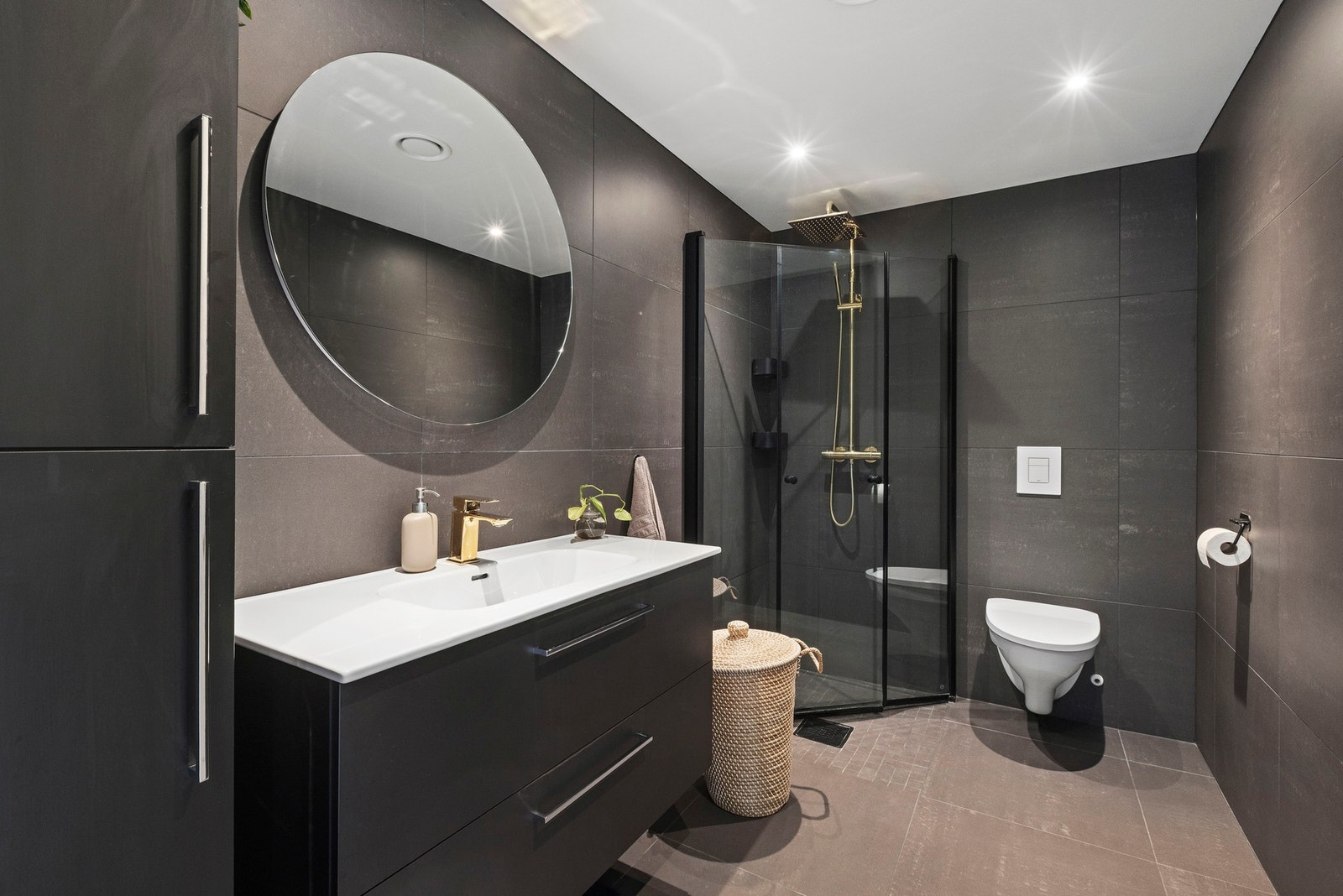 Badet er flislagt med elegante og moderne fliser og har veggopphengt toalett, dusjhjørne, stilfull baderomsinnredning Galleribilde