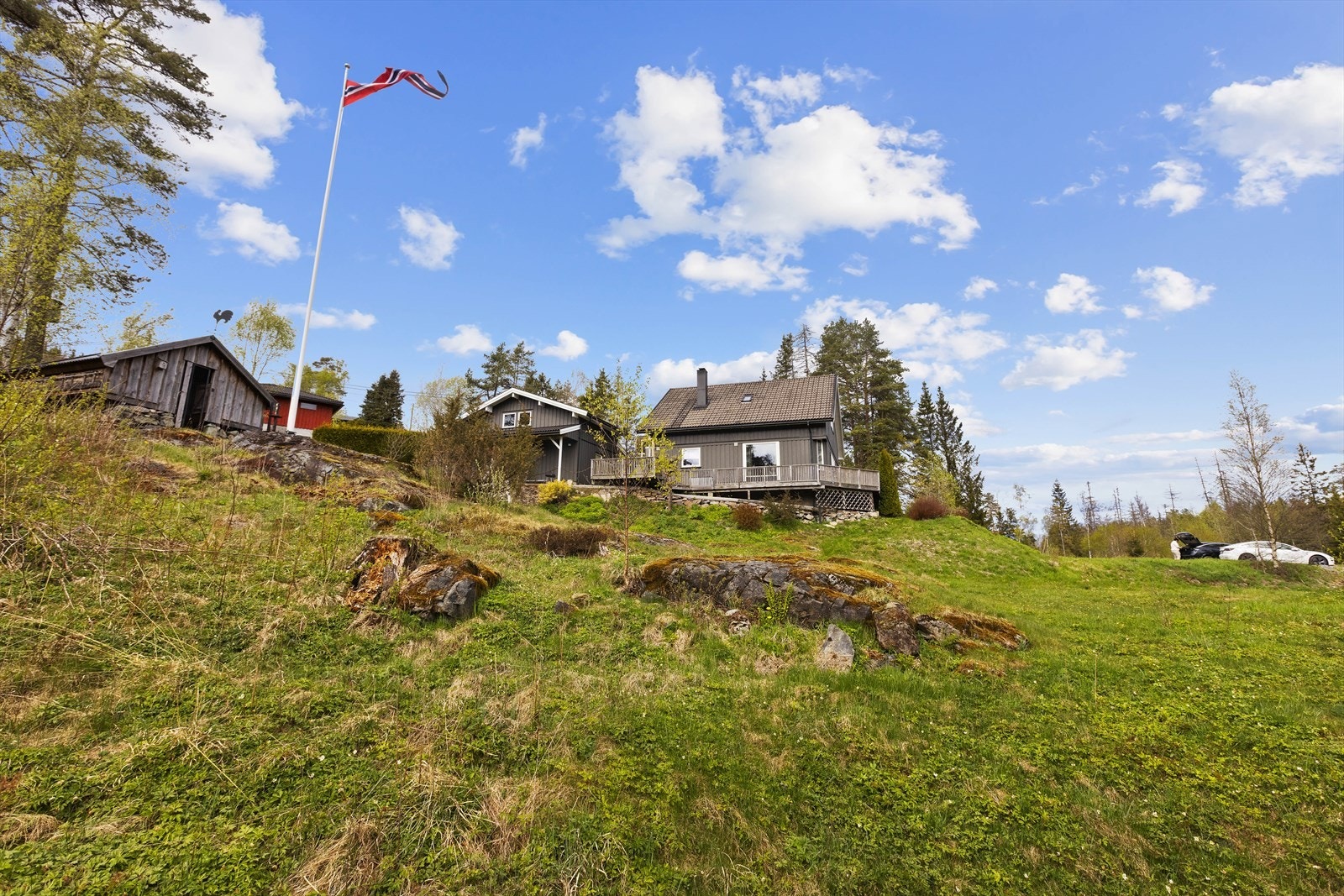 Tomten er skrånende og er opparbeidet med gruslagt gårdsplass, plen, div. beplantning, støttemur av natursteinsblokker mm. Galleribilde