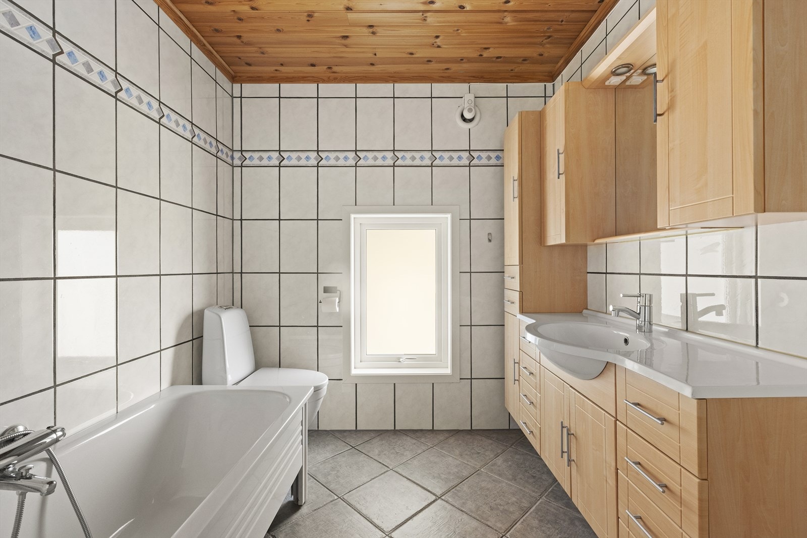 Badet er utstyrt med både badekar og dusjkabinett, samt gulvmontert toalett og innredning. Galleribilde