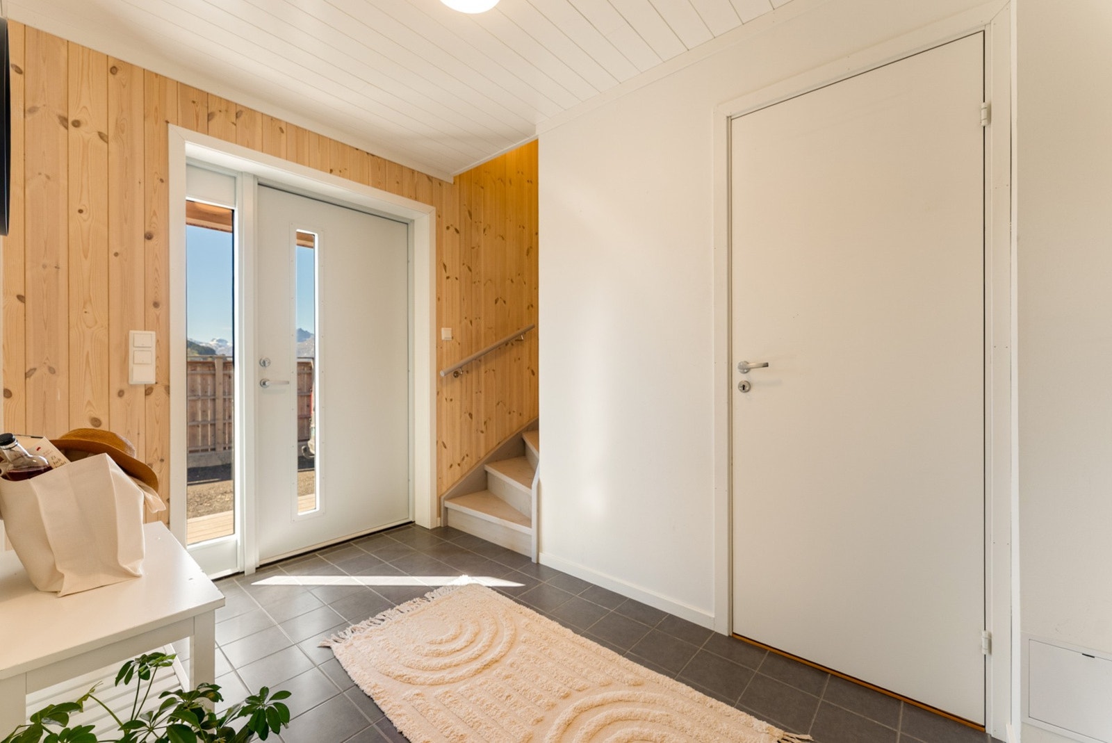 Innbydende entré med flislagt gulv og trapp opp til andre etasje. Galleribilde