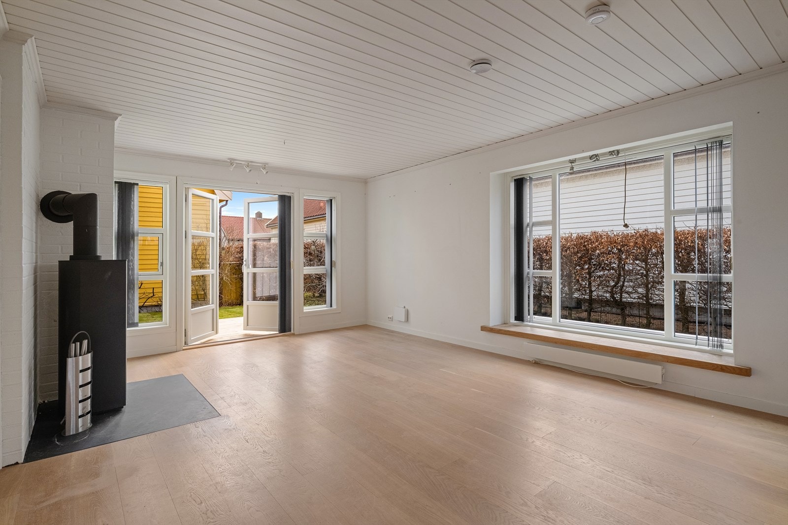 Stuen er boligens naturlige samlingspunkt, med peisovn og utgang til hagen. Galleribilde
