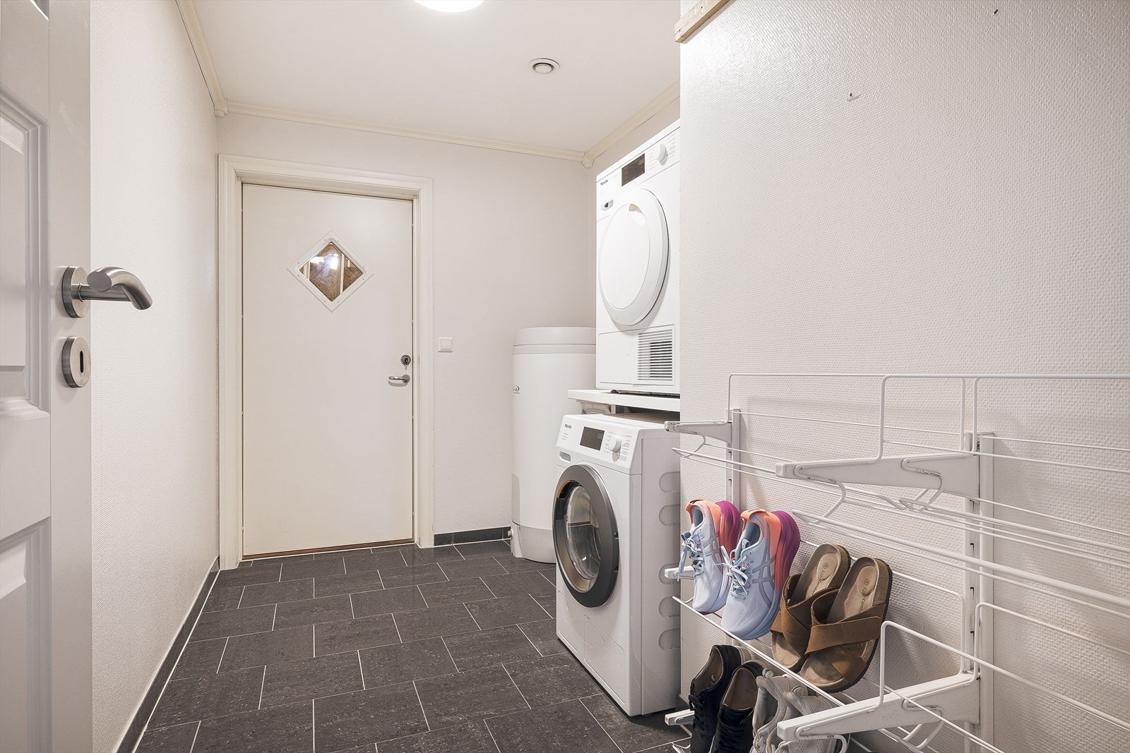 Praktisk vaskerom i første etasje med fliser på gulv, gulvvarme og opplegg for vaskemaskin. Galleribilde