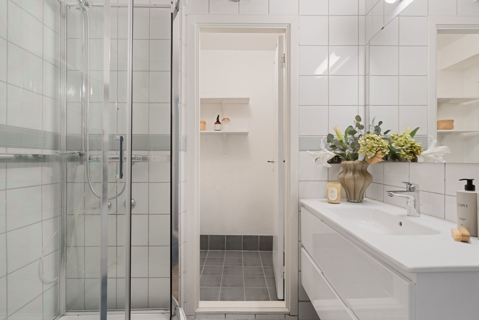 Badet måler ca. 4 m² og er utstyrt med dusjkabinett, flislagt gulv og vegger, samt en nyere baderomsinnredning (satt inn av tidligere eier). Galleribilde