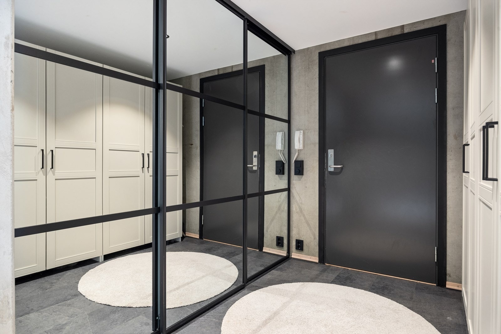 Velkommen inn! Entré med romslig og praktisk garderobeinnredning med speilfronter i sort ramme, som strekker seg fra gulv til tak. Galleribilde