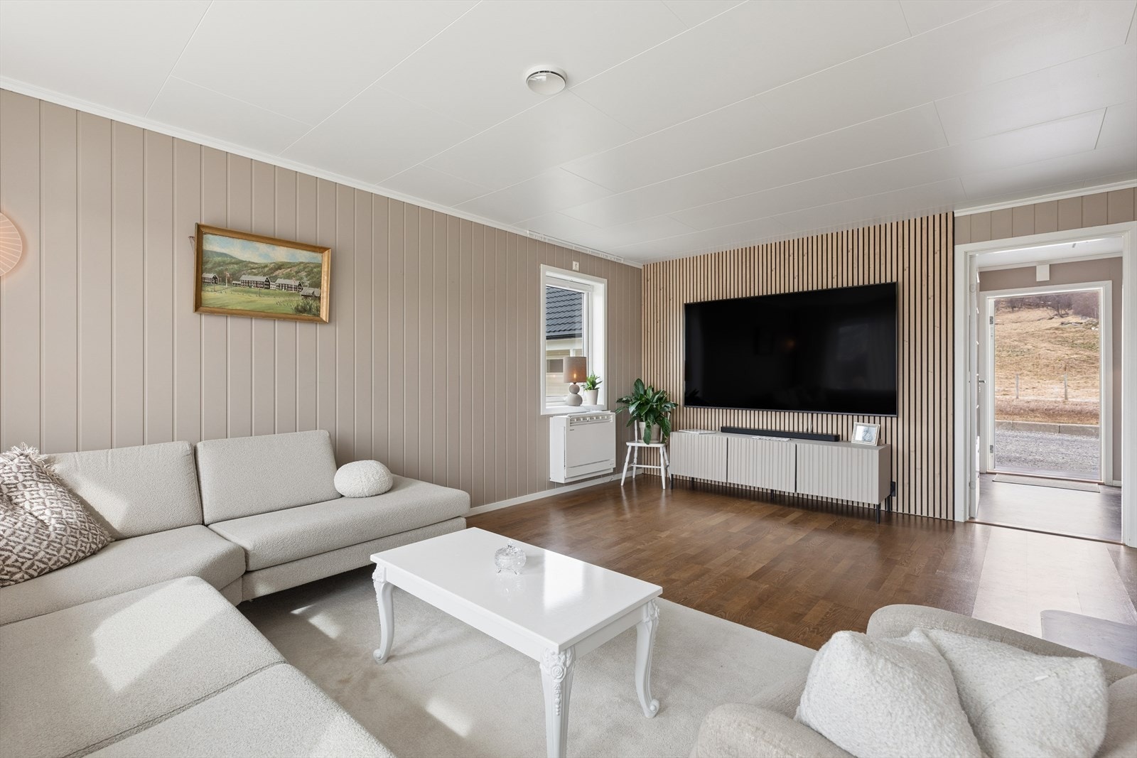 Stuen har god plass til en romslig sofagruppe. Spileveggen skaper en moderne sone for TV-en. Galleribilde