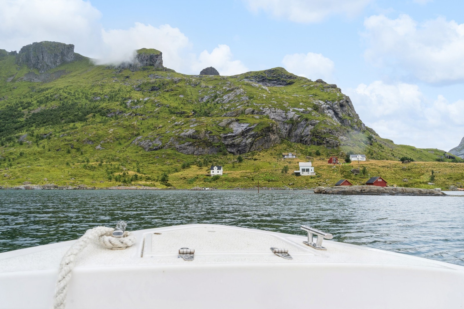 Ankomsten med båt gjennom Reinefjorden er en opplevelse i seg selv, med utsikt til ikoniske Lofotfjellene. Galleribilde
