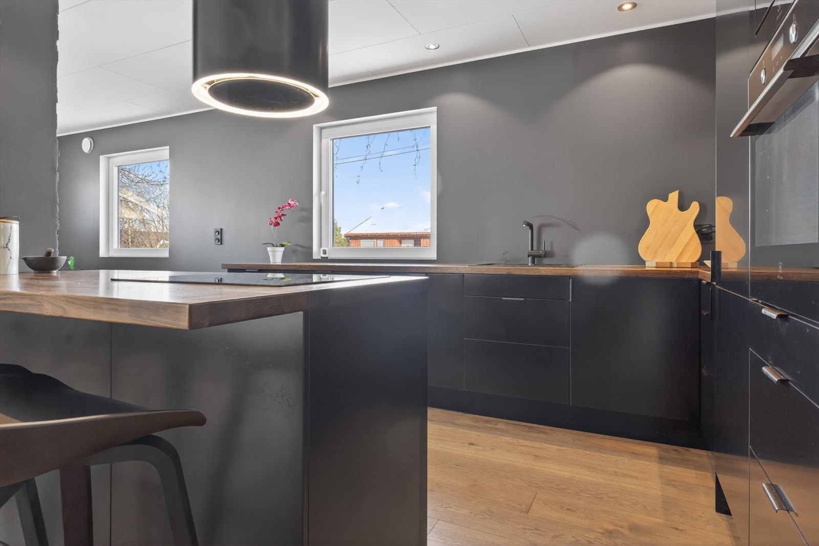Moderne kjøkken med stilren design, store vinduer for naturlig lys, og elegant belysning som skaper en innbydende atmosfære. Galleribilde