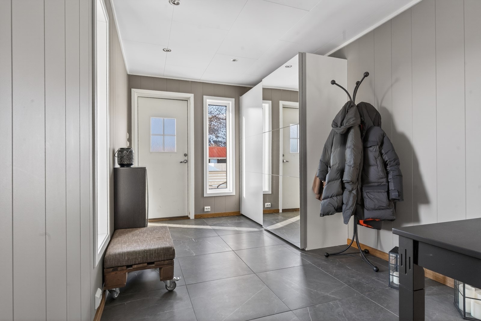 Lys og innbydende entré med stilrene detaljer og praktisk speil. Perfekt for å ønske gjester velkommen inn i ditt hjem. Galleribilde