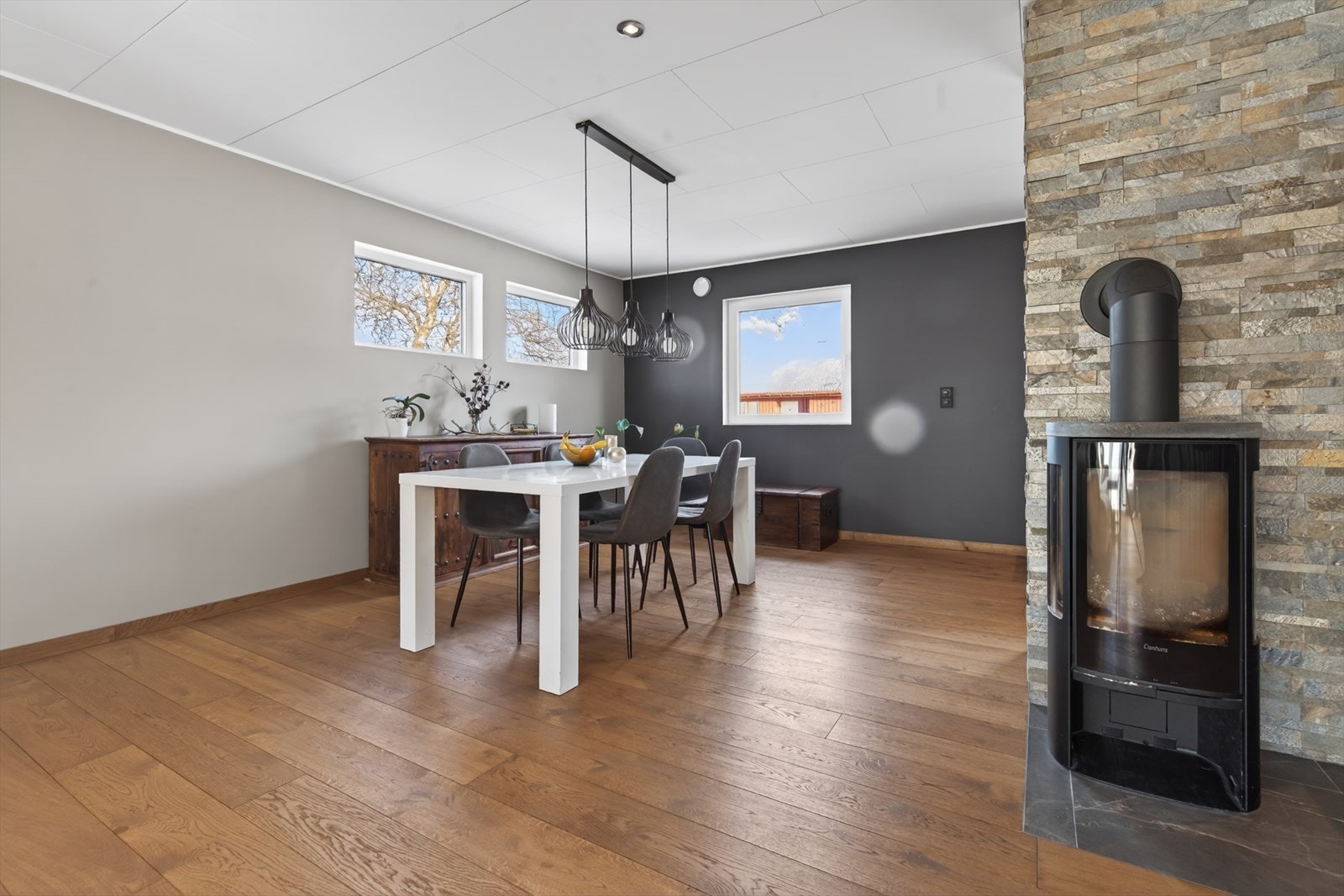 Moderne spisestue med stilrent design og peis. Store vinduer gir naturlig lys og en innbydende atmosfære. Galleribilde