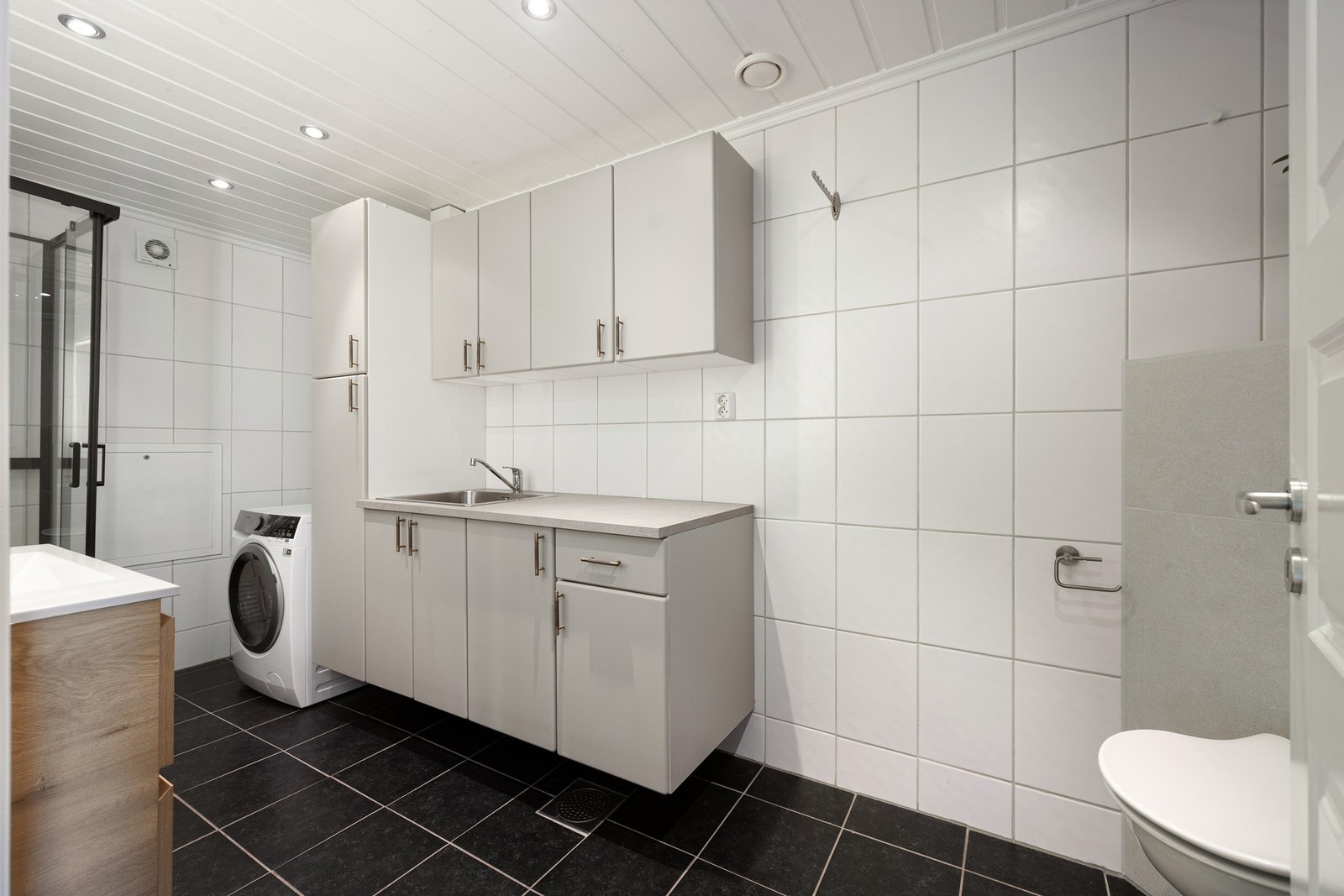 Lang benk med nedfelt vaskekum og skap gir gode oppbevarings- og arbeidsflater. Badet ble opprinnelig etablert i 2005 og har fått enkelte oppgraderinger i 2025/2026. Galleribilde