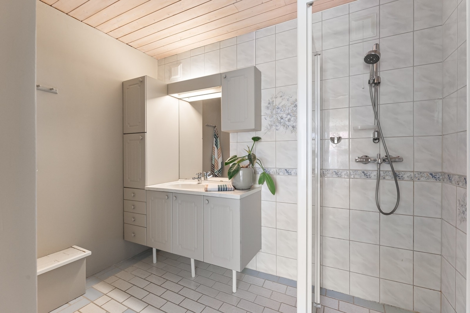 Badet i underetasjen er fra byggeåret, med flislagt gulv med gulvvarme og dusj på gulv med glassdør. Galleribilde