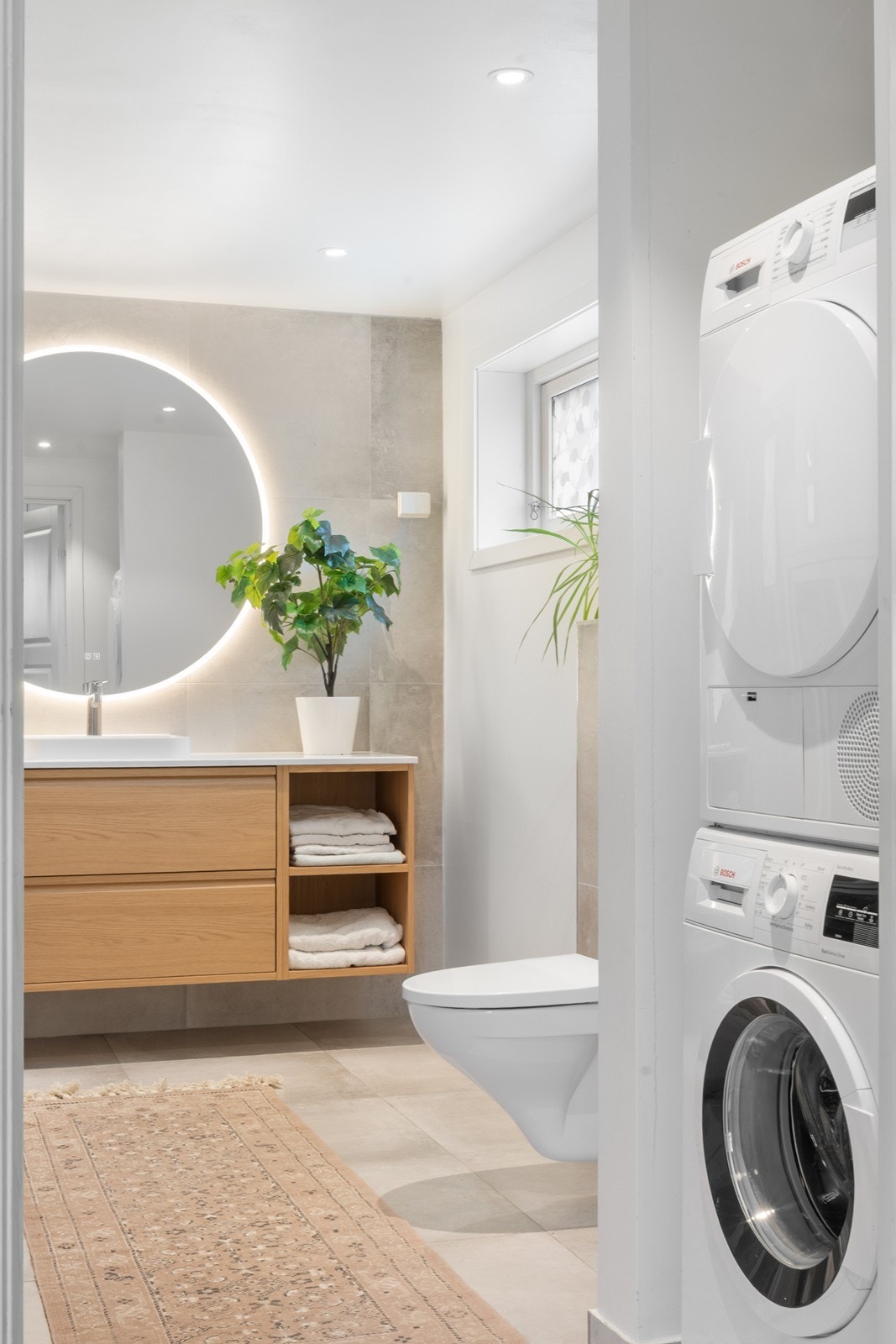 Over servanten er det montert et stort speil med integrert belysning, supplert med downlights i himling. Videre har badet en praktisk nisje med plass til vaskemaskin og tørketrommel. Galleribilde