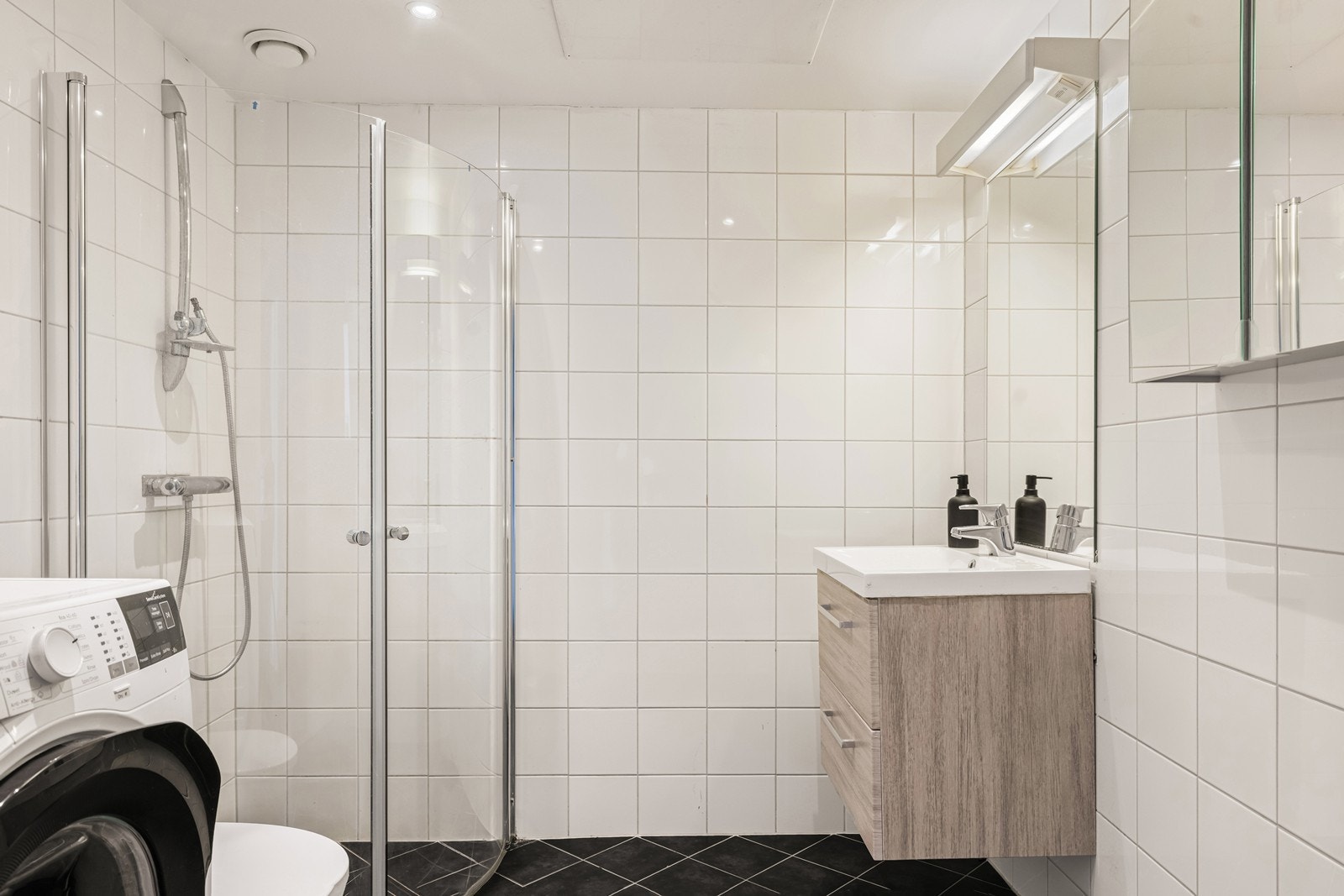 Pent, flislagt bad med downlights i himlingen og opplegg for vaskemaskin. Galleribilde