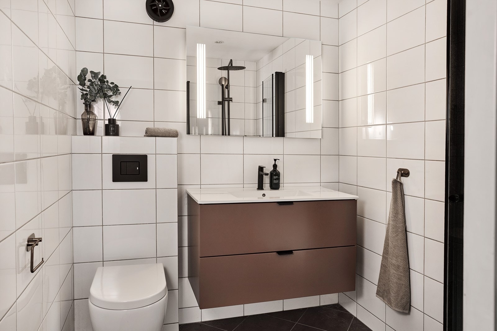 Moderne baderom med vegghengt toalett, romslig innredning og integrert belysning i speilet. Galleribilde