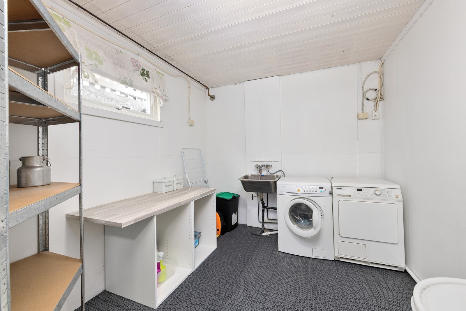 Praktisk vaskerom i kjelleren med opplegg for vaskemaskin og skyllekum i stål. Galleribilde