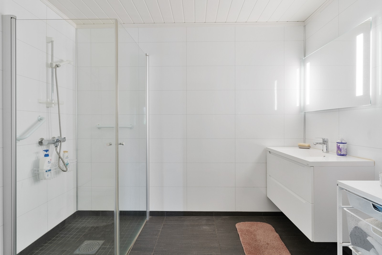 Badet er innredet med servant, speil med innebygget belysning, toalett og dusjhjørne. Galleribilde