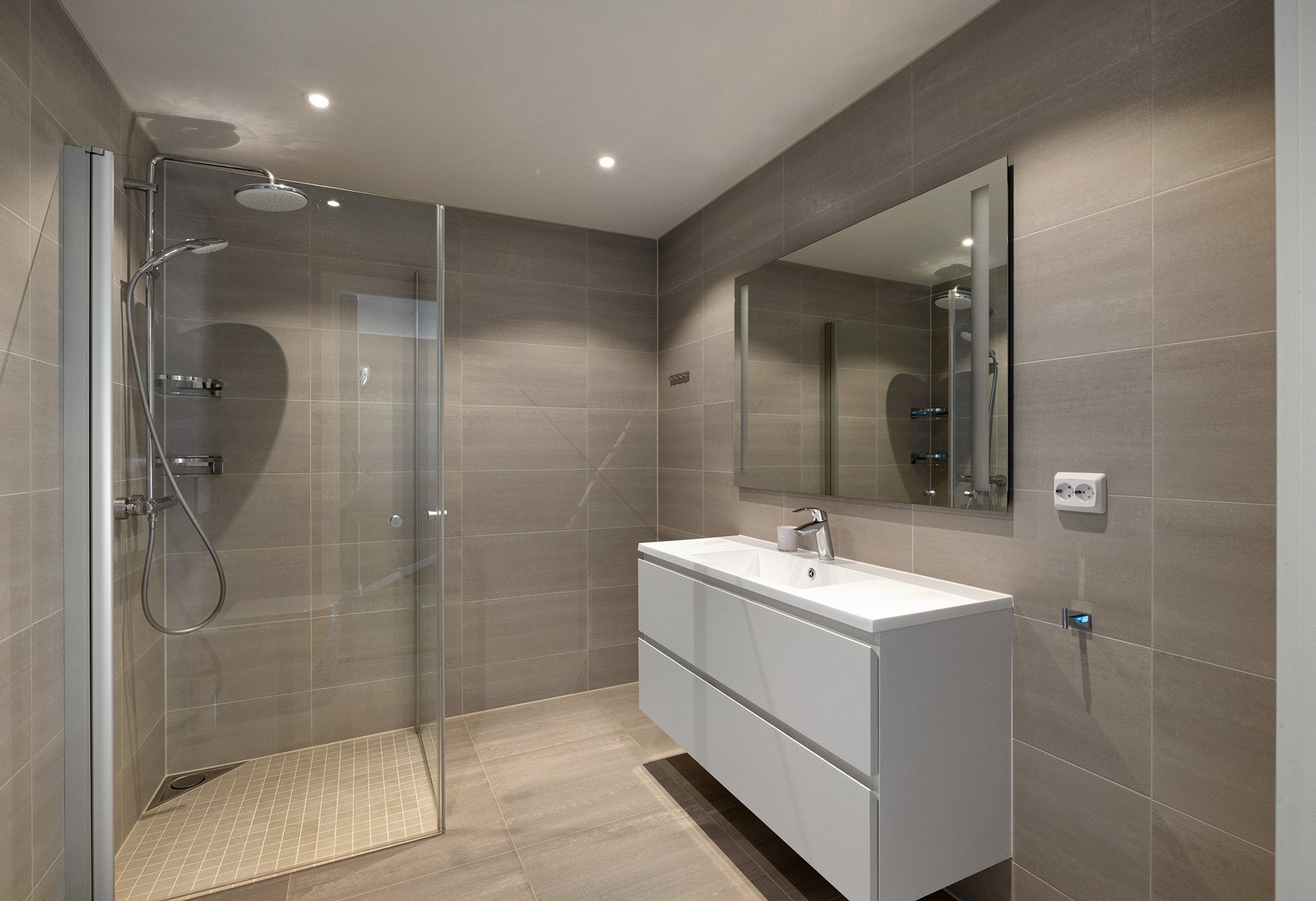 Fra stuen er det inngang til et bad, også dette badet har fliser på gulv og vegger. Galleribilde
