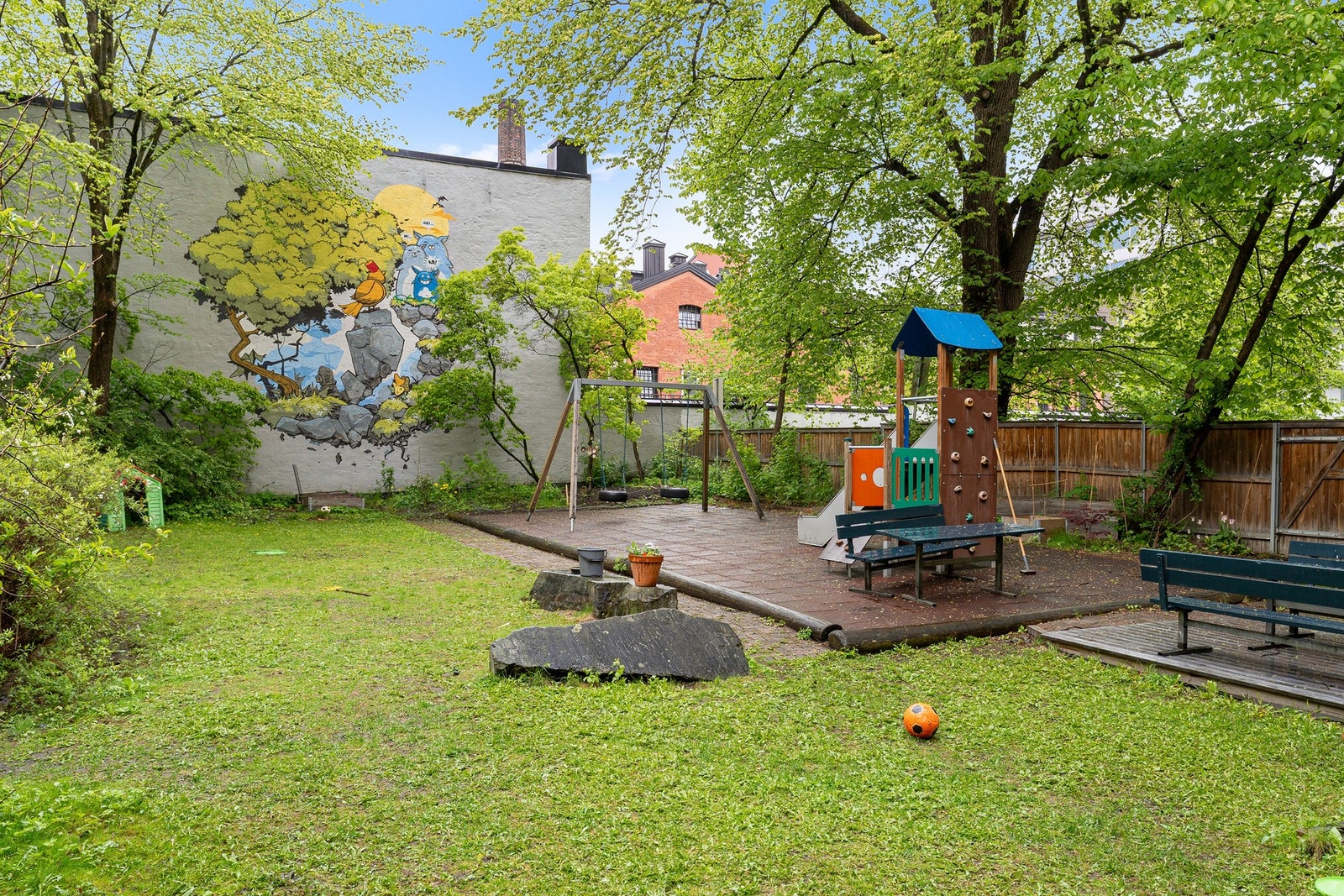 Stor og hyggelig bakgård med sittegrupper, lekestativ, stor grill, plen og beplantning Galleribilde