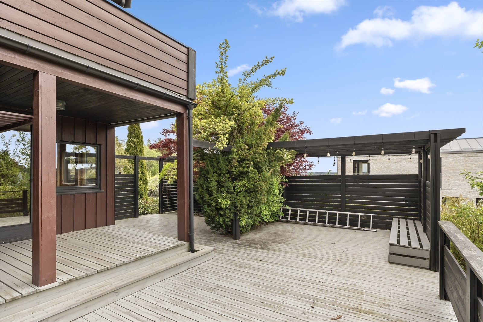 Stor terrasse med pergola, levegger og flere hyggelige soner for utemøblering. Galleribilde