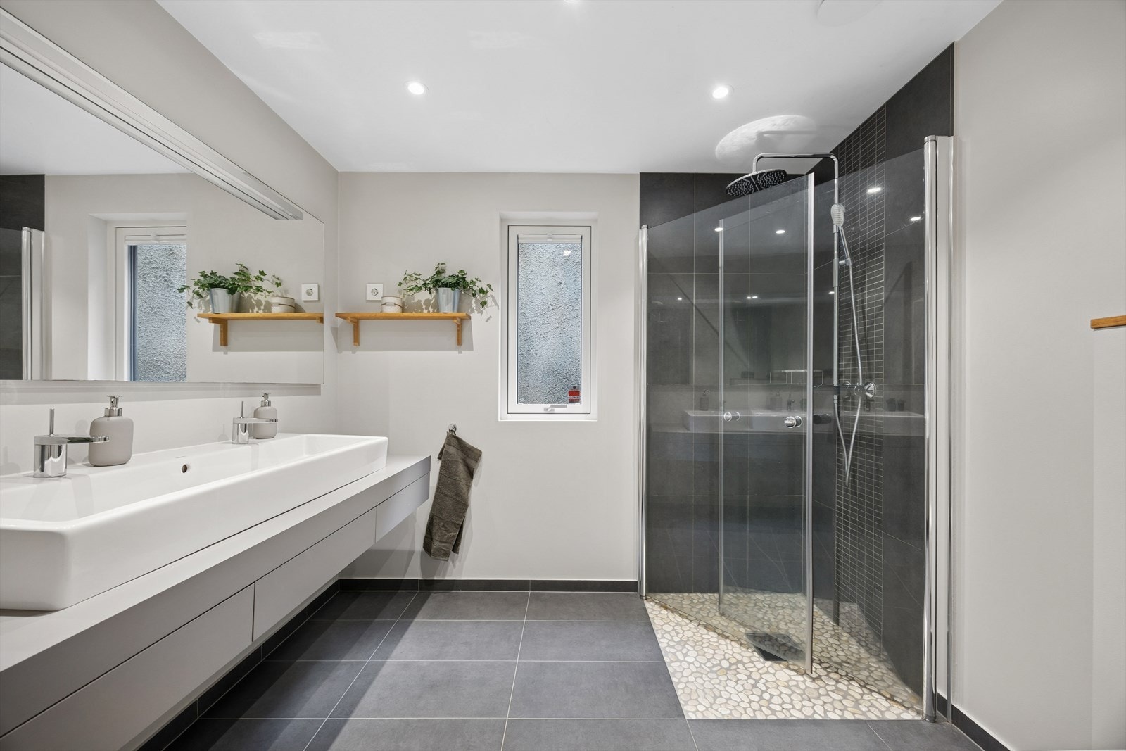 Badet i underetasjen er også utstyrt med vegghengt toalett, dusjhjørne med svingbare glassdører, og heldekkende servant med tilhørende skuffeinnredning. Galleribilde
