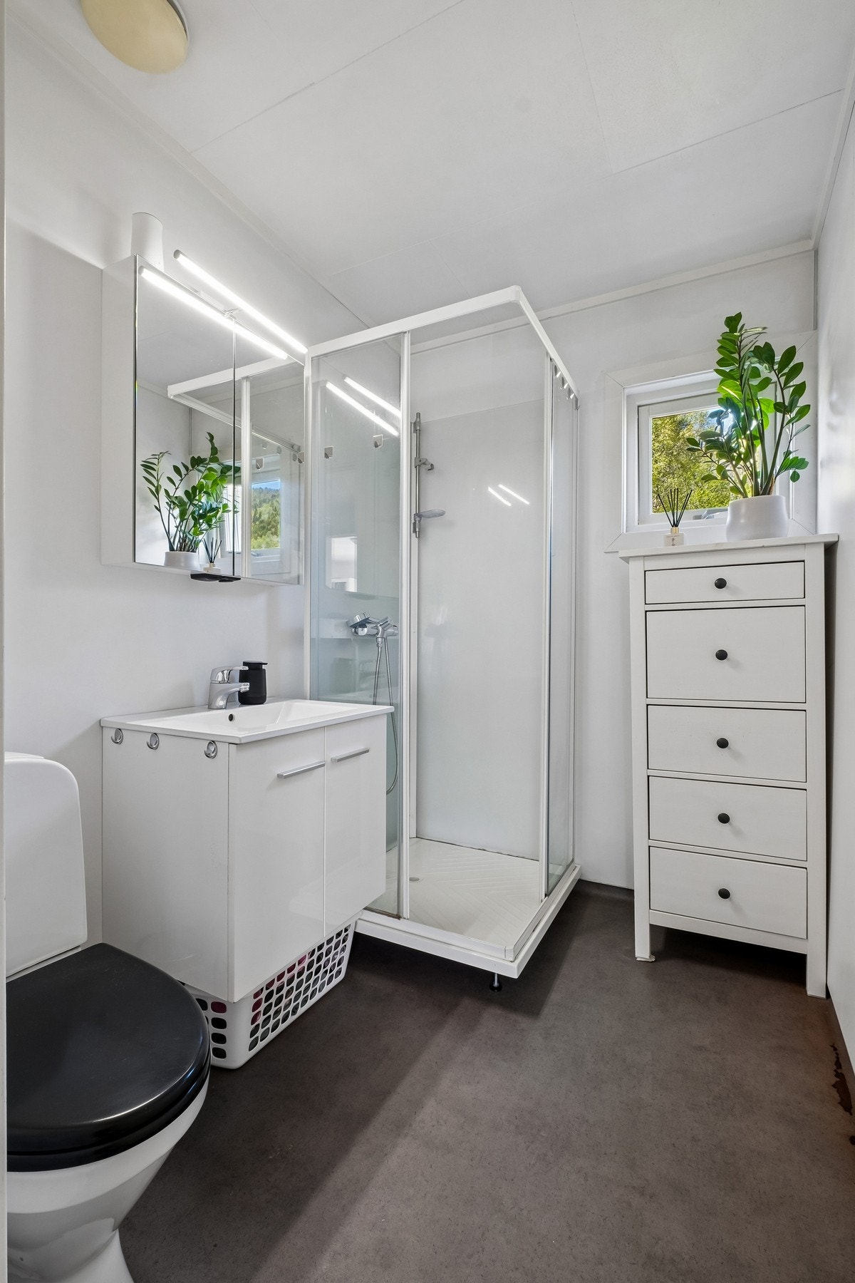 Badet er utstyrt med varmekabler i gulvet, servantinnredning, gulvmontert toalett og dusjkabinett Galleribilde