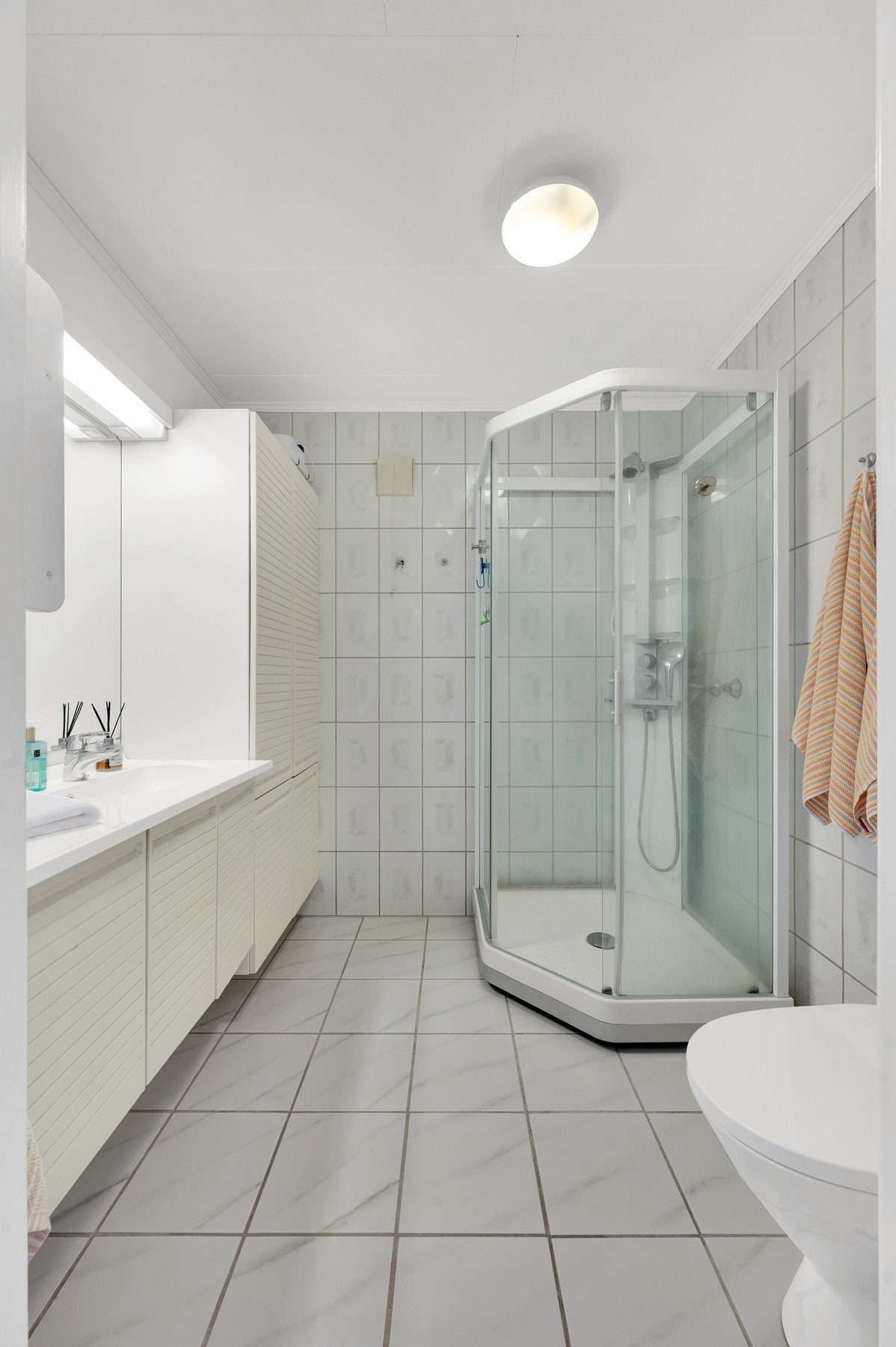 Badet i underetasjen har keramiske fliser på vegger og gulv. Det er varme i gulvet og dusjkabinett. Foto: H5 Galleribilde