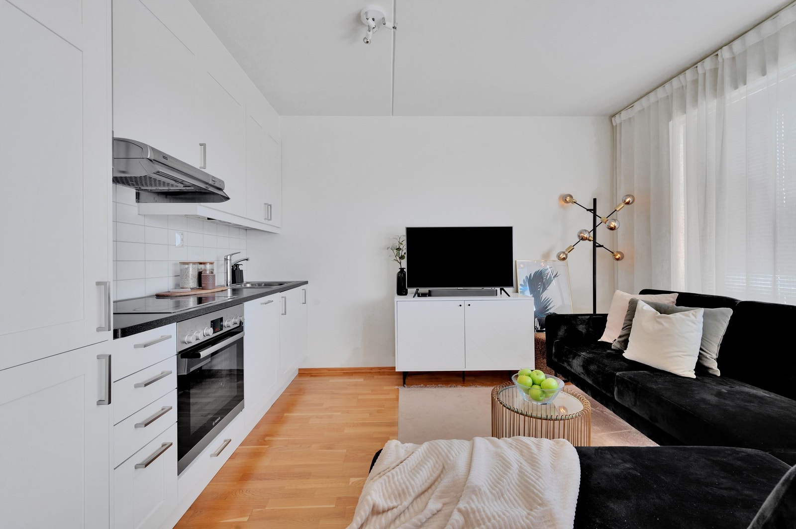 Moderne kjøkken i åpen løsning mot stuen, med hvite skapfronter og benkeplater i laminat. Galleribilde