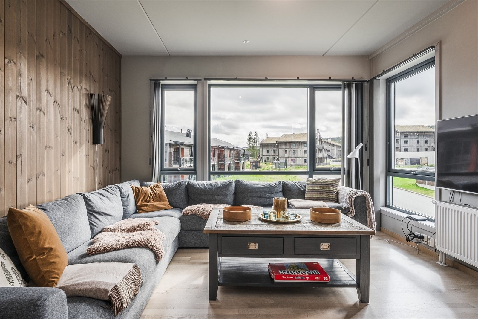 En kombinasjon av eikeparkett og panelvegger gir en lun og moderne atmosfære i oppholdsrommet. Galleribilde