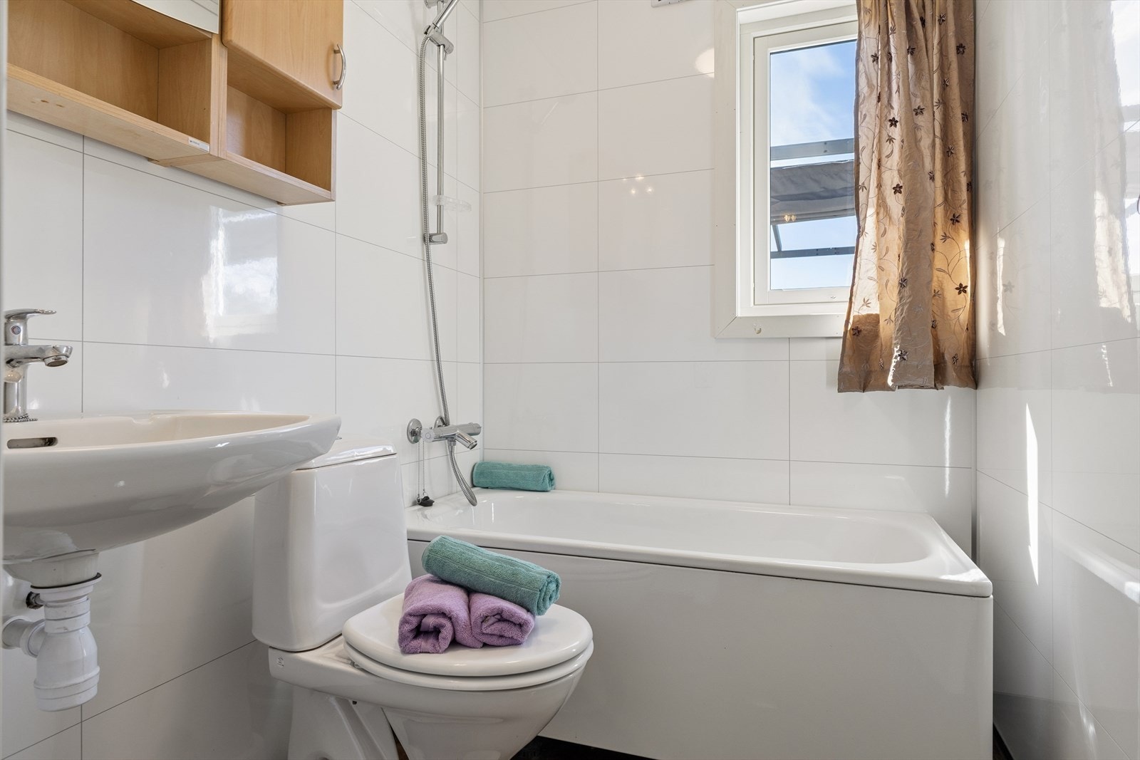 Badet er utstyrt med badekar, servant og gulvmontert toalett. Ventilasjon skjer via elektrisk avtrekksvifte. Galleribilde