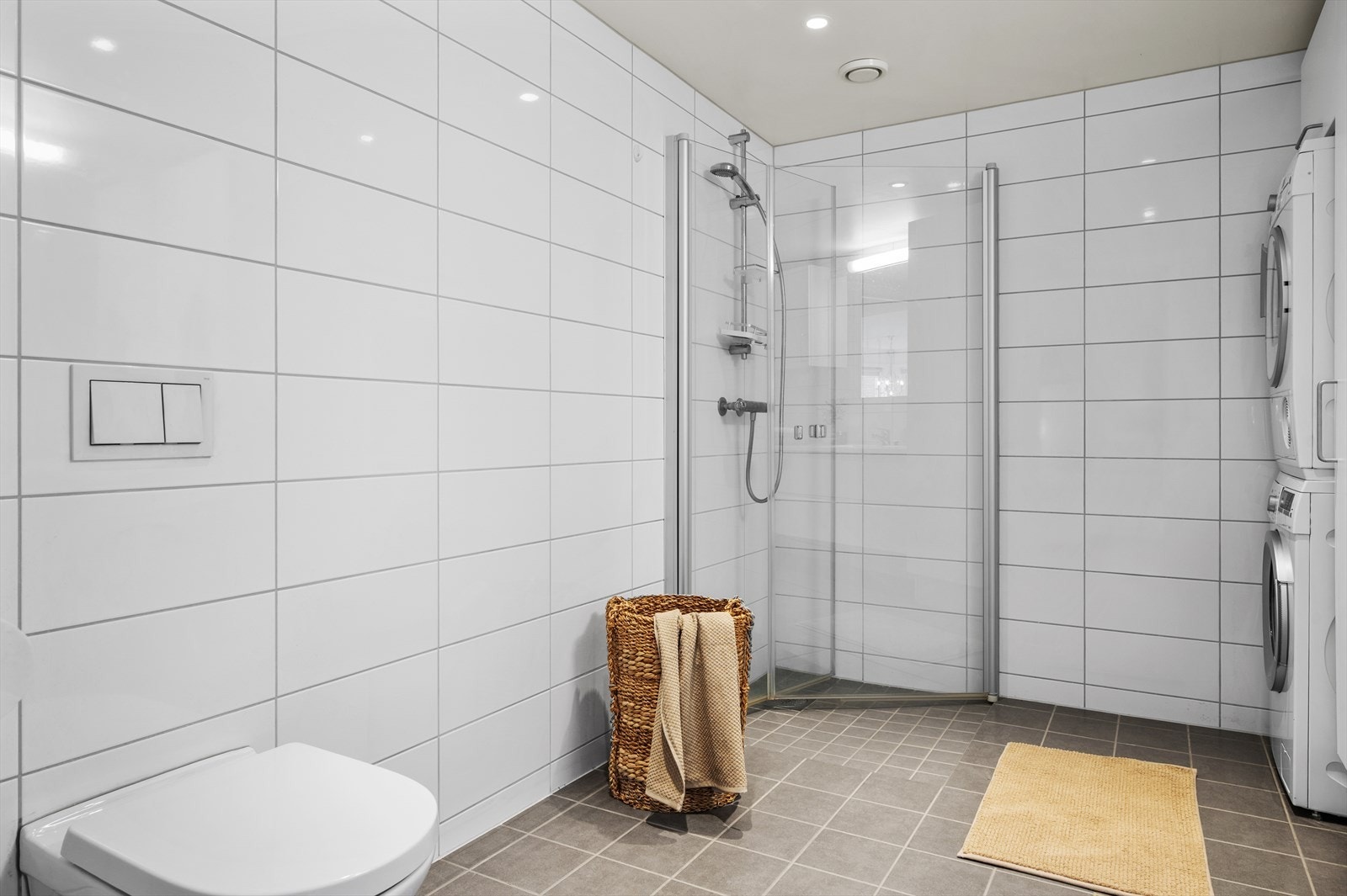 Badet er utstyrt med vegghengt toalett, dusjhjørne, rikelig med skap-/benkeplass og opplegg for vaskemaskin. Galleribilde