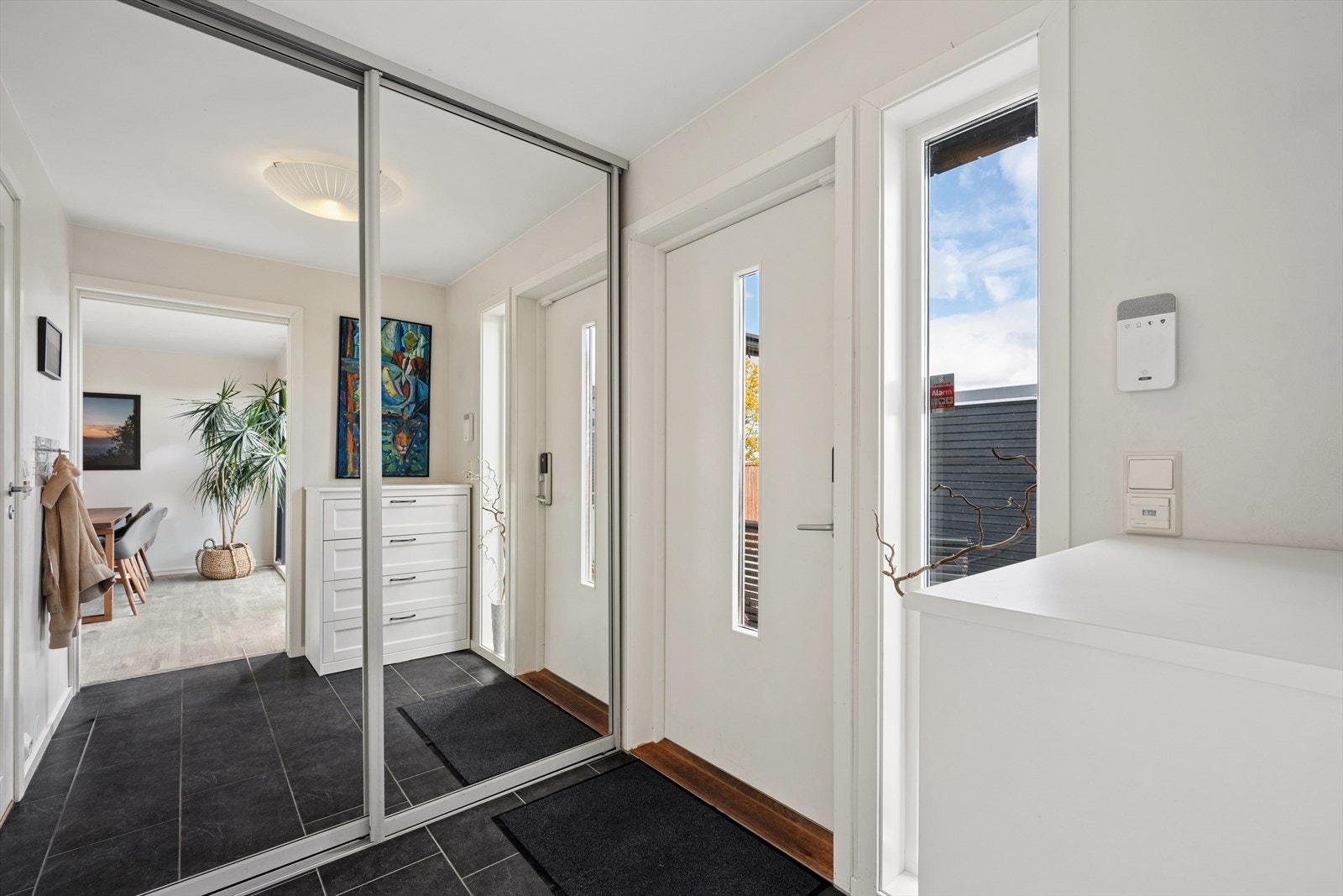 Man ønskes velkommen inn i en romslig entré som er praktisk innredet med stor skyvedørsgarderobe som gir god lagringsplass til familiens yttertøy og sko. Galleribilde