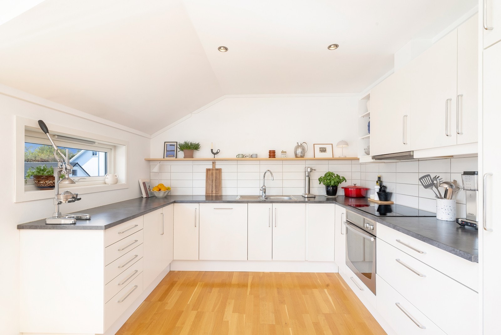 Flott lyst kjøkken med moderne innredning med hvite fronter og grå laminert benkeplate. Galleribilde
