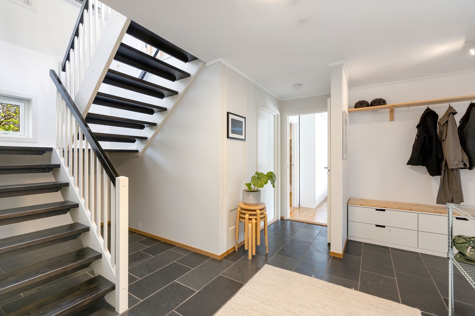 Romslig gang/entrè med fliser på gulv og malte vegger i lyse farger. Galleribilde