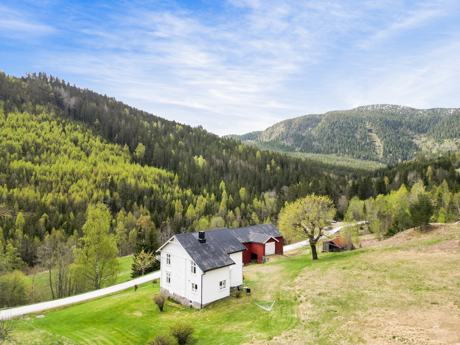 Boligen ligger i skrånende terreng med en stor og åpen hage. Galleribilde