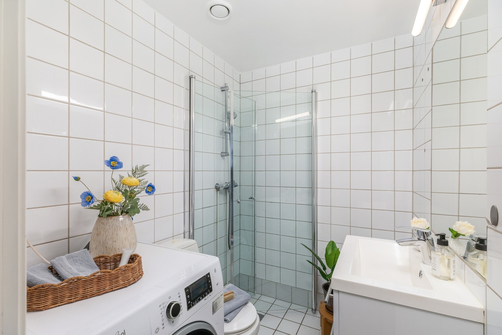 Badet er flislagt og har varmekabler, dusj med inn-/utadslående glassdører, servant med underskap, speil med overlys og vegghengt oppbevaring. Galleribilde
