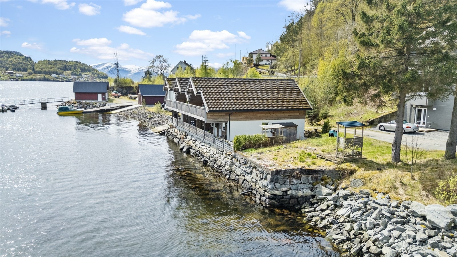 Eigedommen ligg heilt i sjøkanten med mur av naturstein mot fjorden Galleribilde