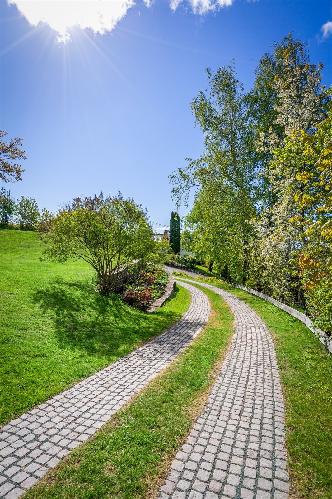 Mur i oppkjørsel og blomsterbedd, håndbygget i stein med Røykengranitt. Galleribilde