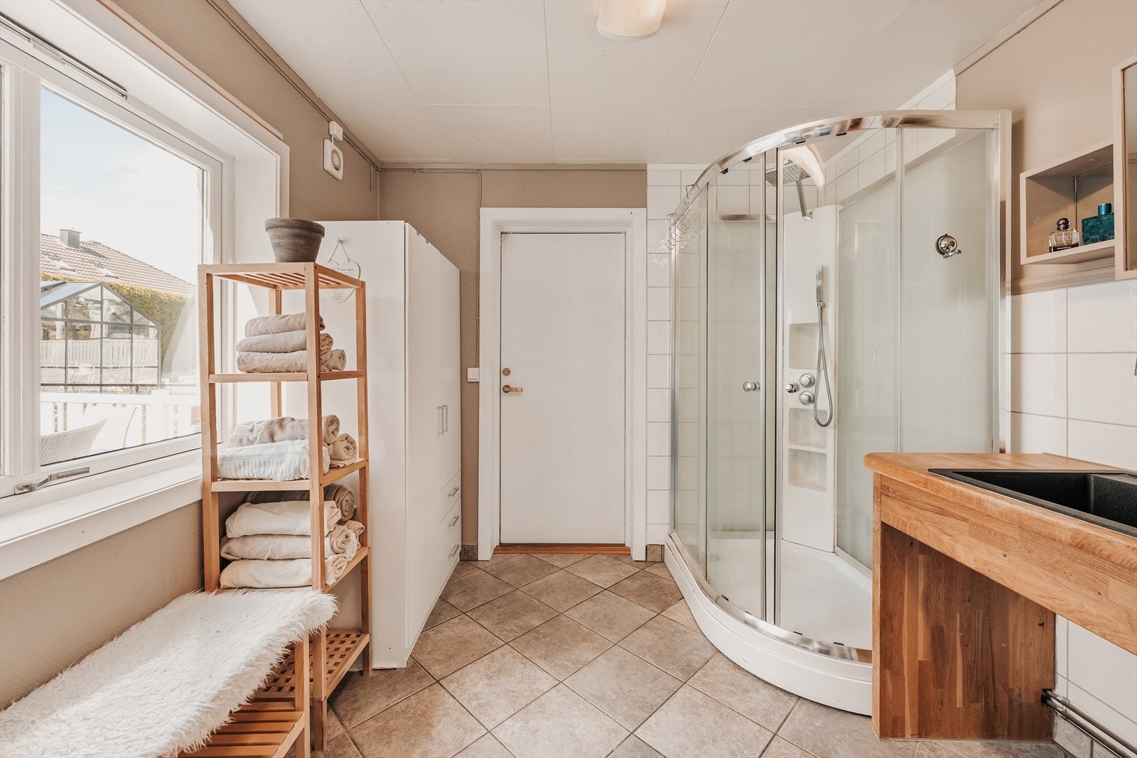 Badet i 1.etasje har fliser på gulv og er innredet med servant og dusjkabinett. Galleribilde