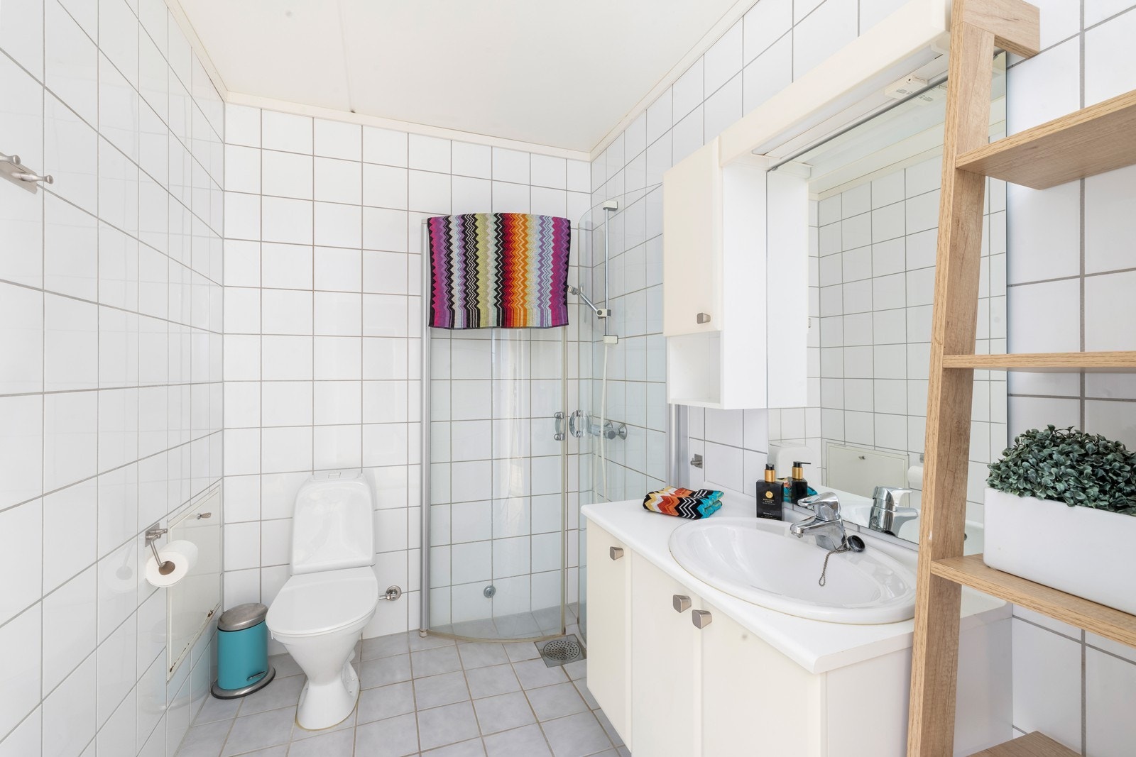 Flislagt bad med varme i gulv. Badet har dusjhjørne, toalett og servant med underskap. Galleribilde