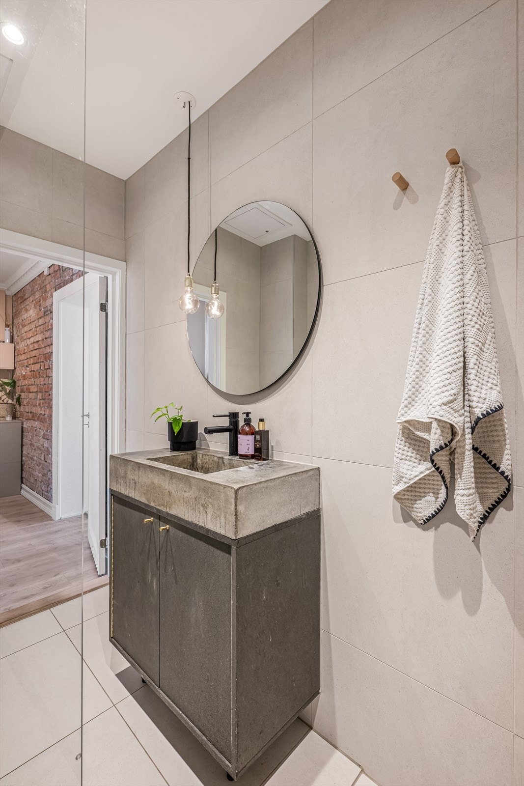 Badet består av heldekkende servant i betong på underskap med fronter i farget MDF, speil med integrert lysarmatur, veggmontert klosett, nedsenket dusjhjørne med fastvegg, termostatstyrt dusjbatteri og dusjutstyr, samt opplegg for vaskemaskin. Galleribilde