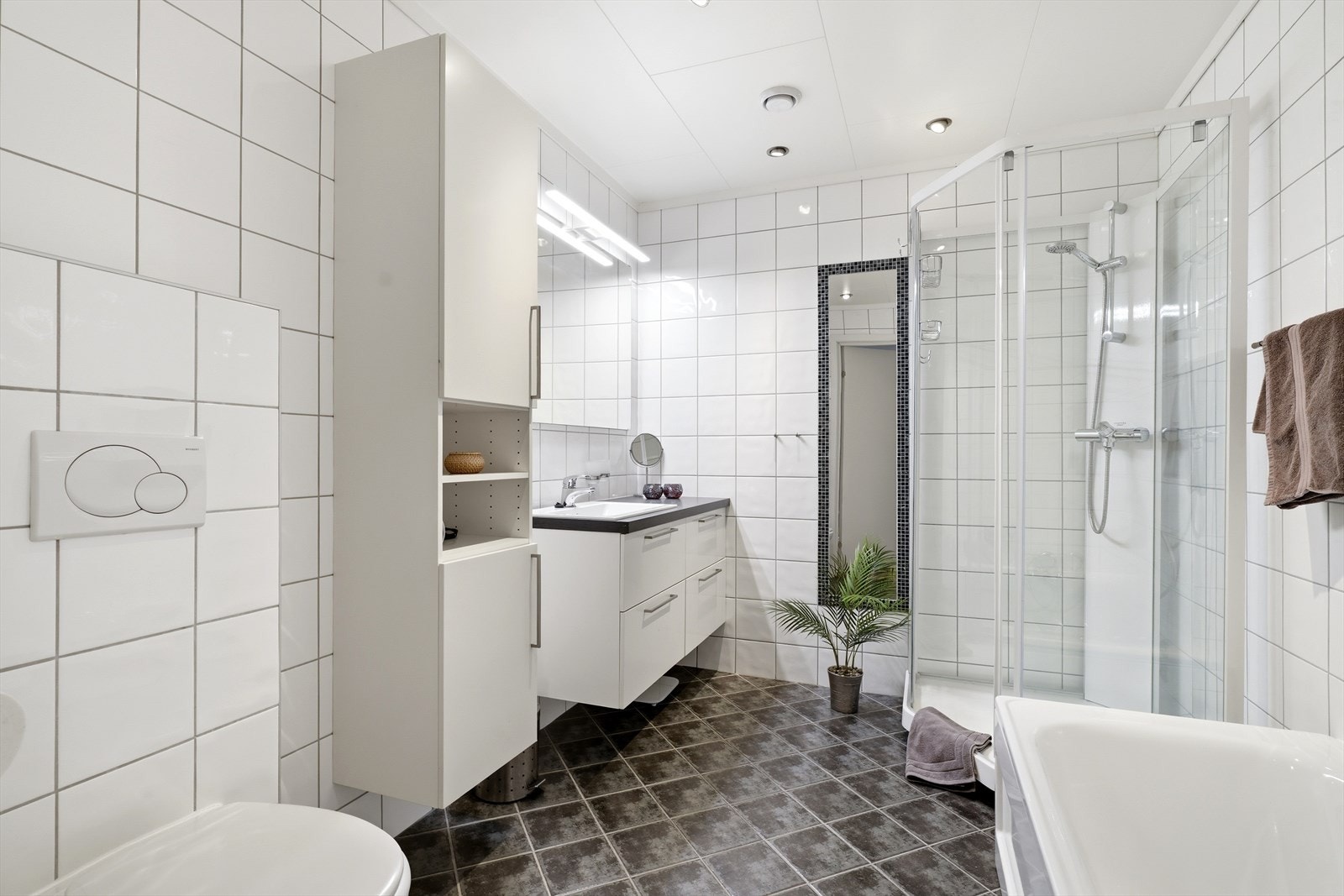 Badet i underetasjen er innredet med nedfelt servant, veggmontert toalett, dusjkabinett og badekar Galleribilde
