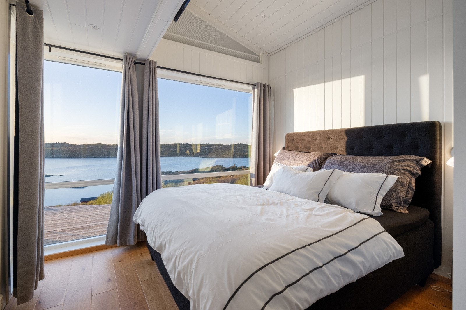 Et av tre soverom, med store vinduer som rammer inn sjøutsikten. Galleribilde