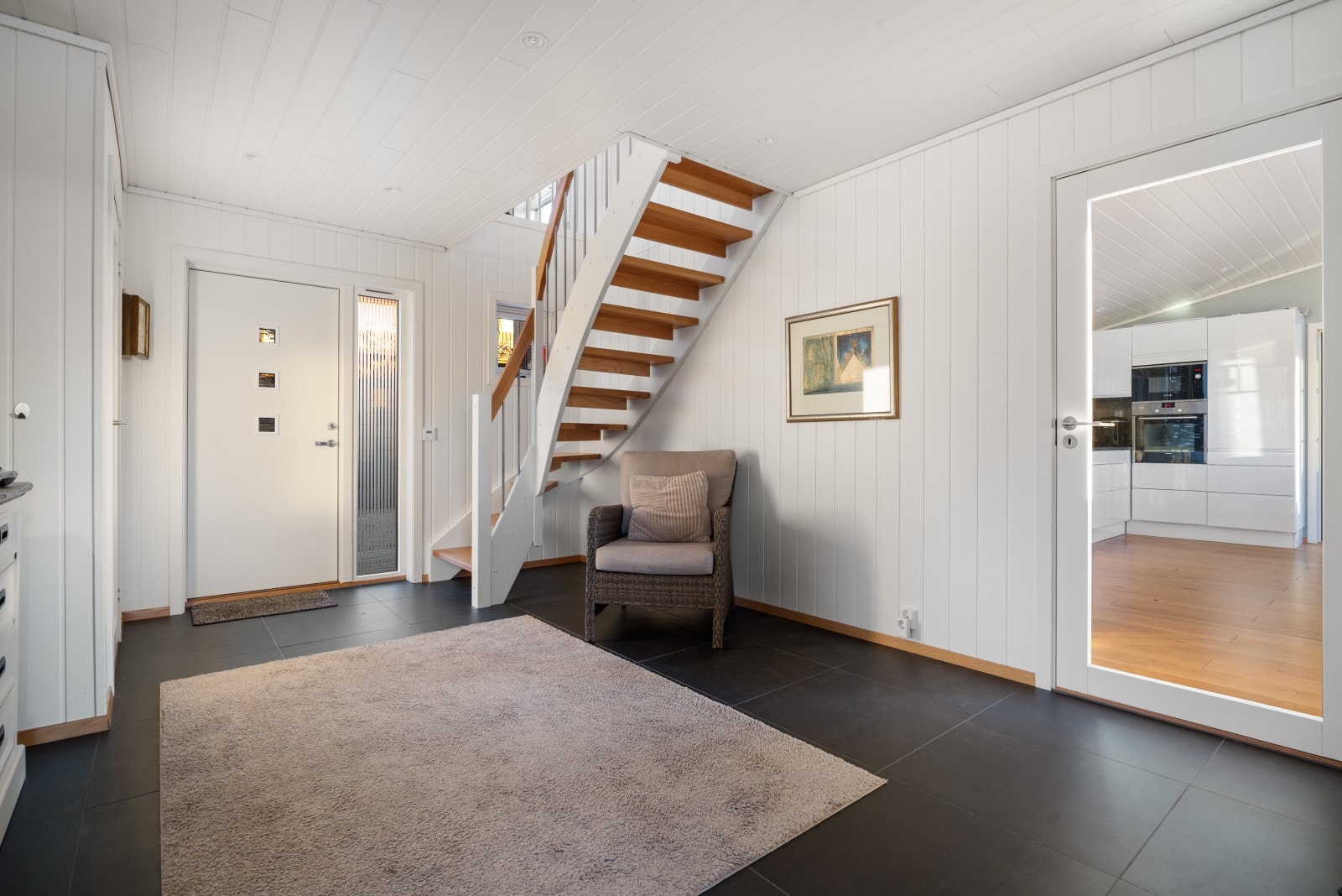 Fra gangen er det glassdør inn til kjøkkenet og en åpen svingtrapp med eiketrinn opp til hemsen. Galleribilde