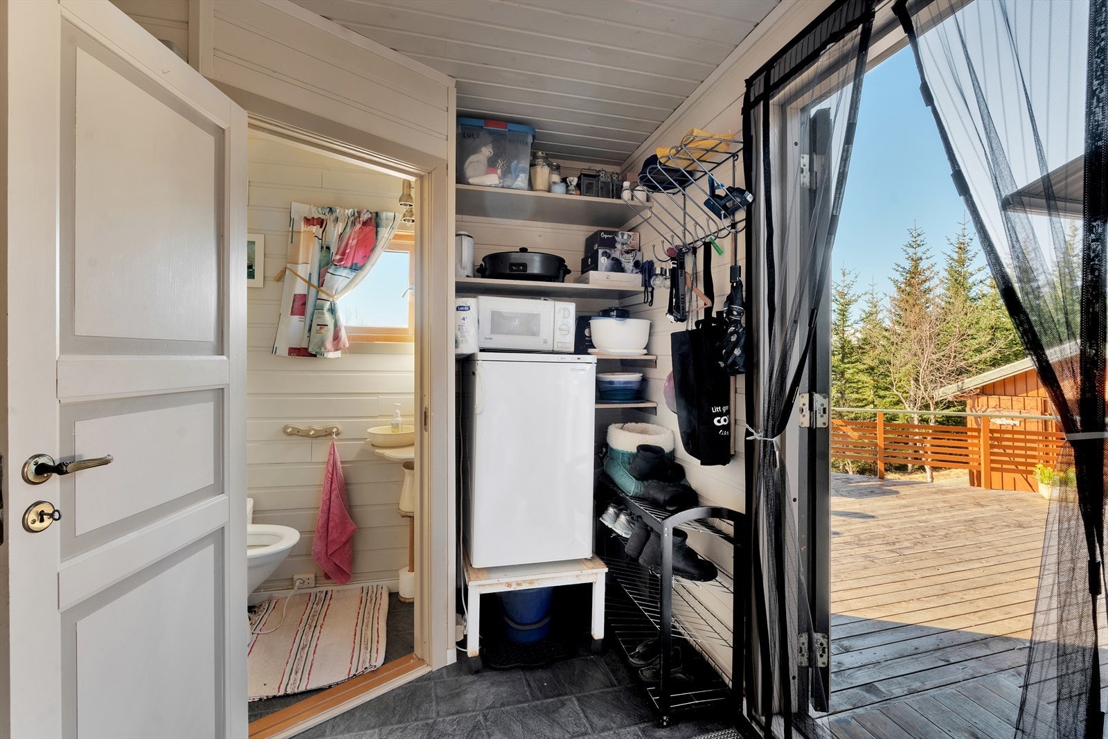 Utgang fra gang til romslig og solrik terrasse vendt mot sjøen. Galleribilde