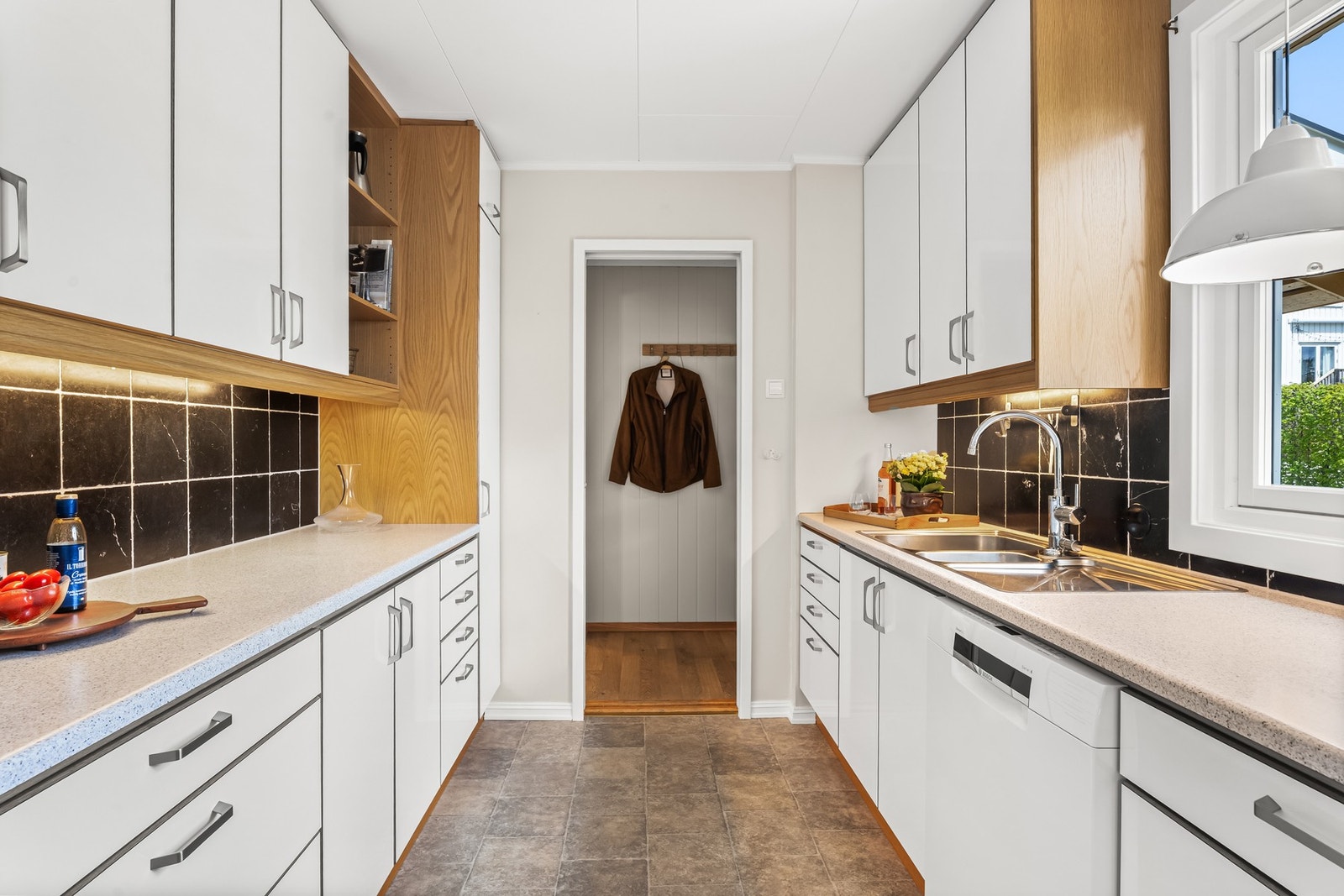Kjøkkenet ligger i eget rom, tilknyttet stuen og med skyvedør mot entreen. Veggene er lysmalte og gulvet er i praktisk linoleum med flismønster. Galleribilde