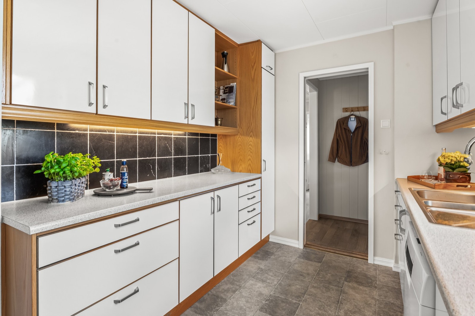 Innredningen fremstår tidsmessig med hvite, glatte fronter, trehvite dekksider og benkeplate i lys laminat med nedfelt vaskekum. Galleribilde
