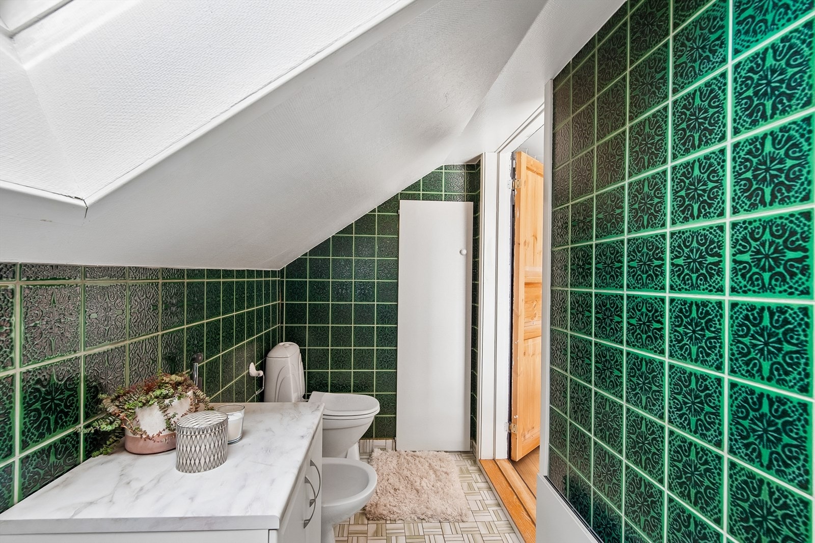 Badet er utstyrt med gulvmontert toalett og bide, og har flislagte vegger og gulv. Galleribilde