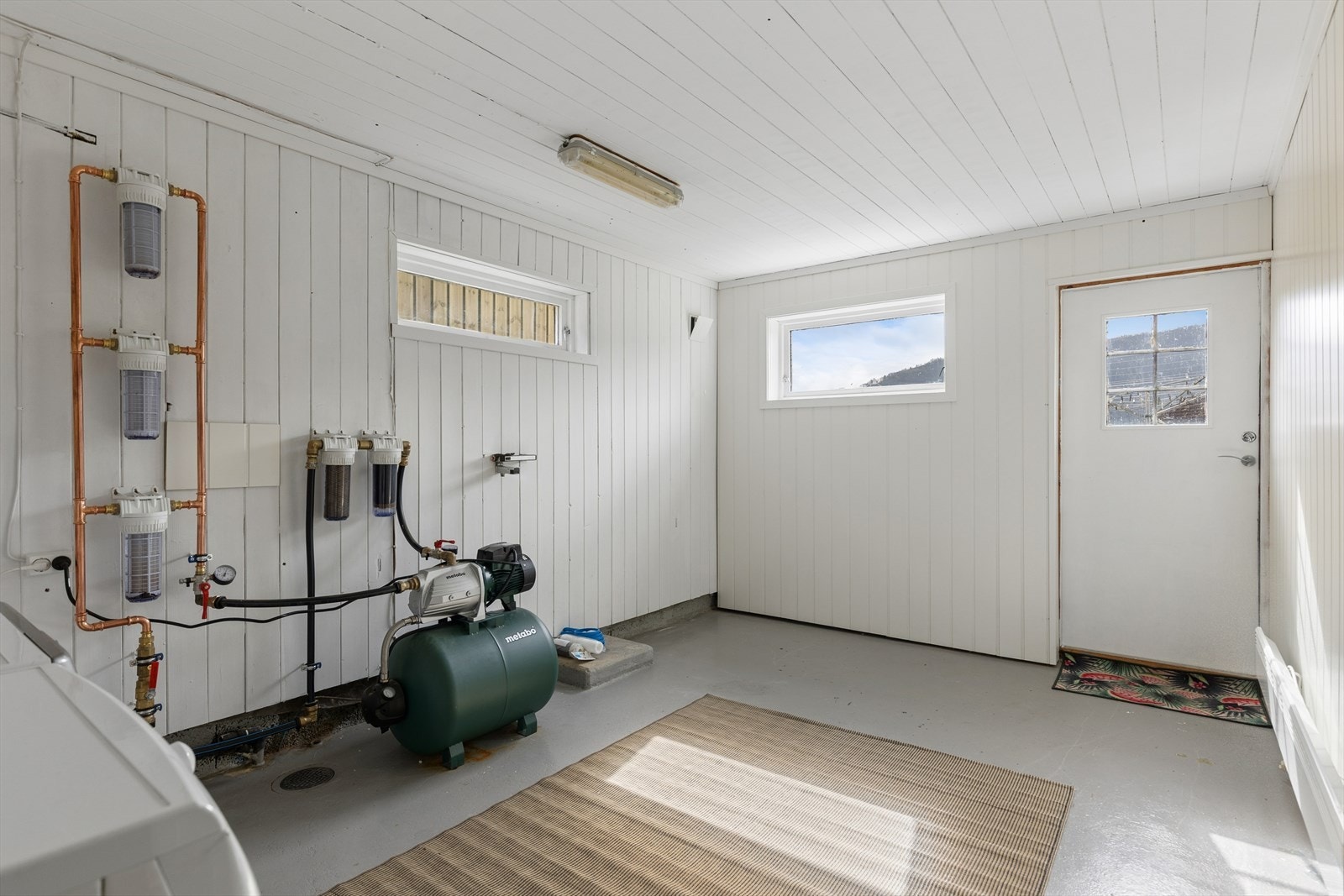 Romslig vaskerom med egen utgang. Her er også boligens private vannpumpe med nytt filtreringsanlegg installert. Galleribilde